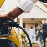 woman charging electric vehicle with family in the background