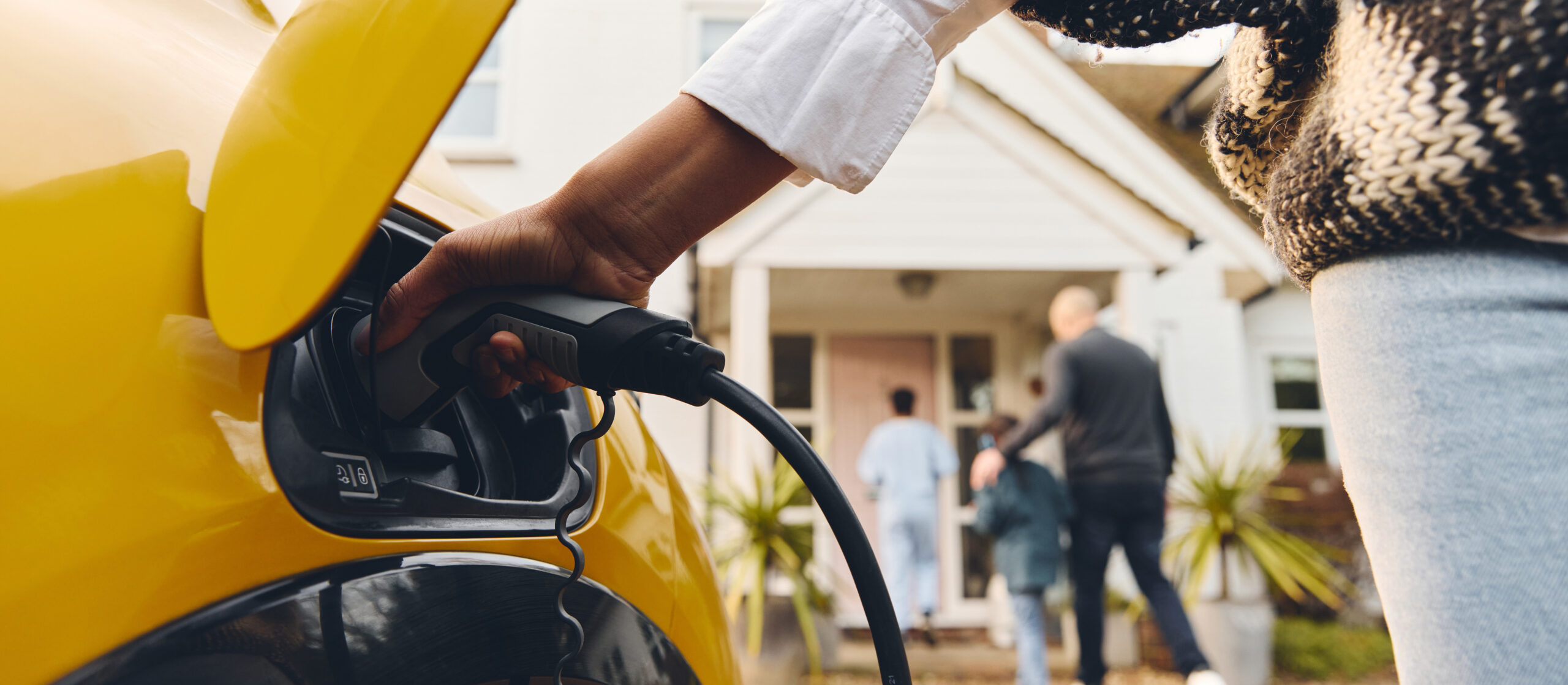 femme qui recharge un véhicule électrique avec sa famille en arrière-plan